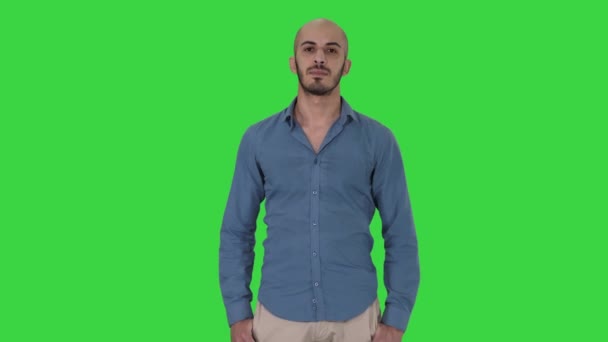 Strenger arabischer Mann, der auf einem grünen Bildschirm steht und in die Kamera schaut, Chroma-Taste. — Stockvideo