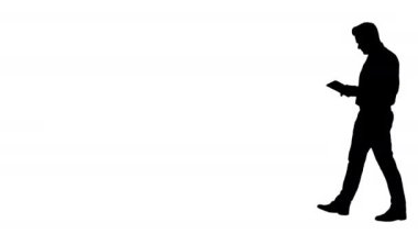 Siluet zarif genç işadamı yürürken tablet kullanıyor..