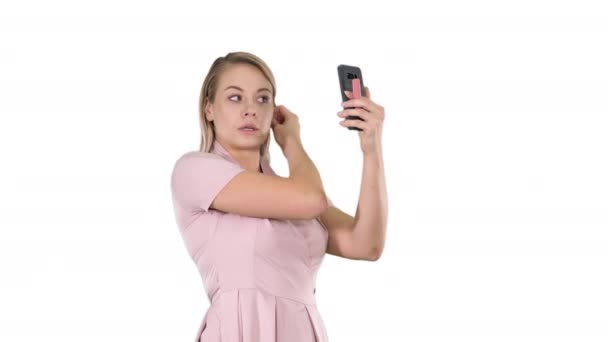 Blond kvinna preening framför smartphone på vit bakgrund. — Stockvideo