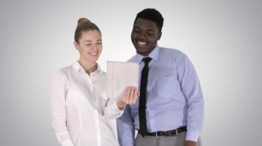 Kafkasyalı genç iş kadını ve Afrikalı meslektaşı gradyan arka planda tabletle video görüşmesi yapıyorlar..