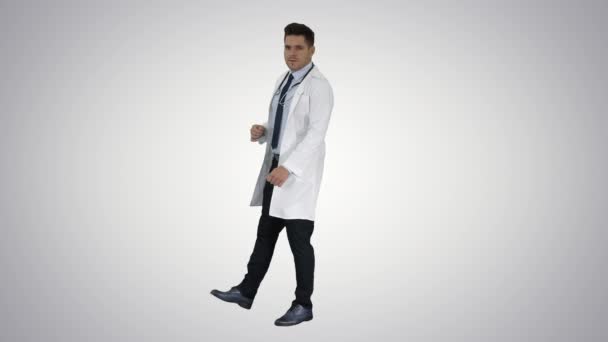 Šťastný doktor ukazuje něco blízko něho a usmívá se na pozadí gradientu. — Stock video