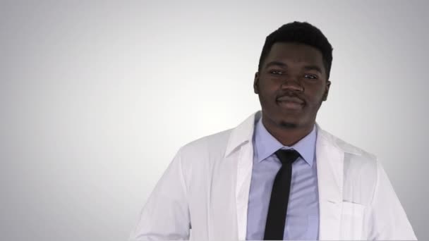 Mannelijke Afrikaanse arts permanent met handen In zijn zakken op de achtergrond met kleurovergang. — Stockvideo