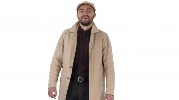 Uśmiechnięty mężczyzna w płaszczu patrzy w kamerę i chodzi po białym tle. — Wideo stockowe