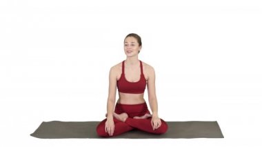 Güzel bir kadın yoga minderinde oturup beyaz arka planda biriyle konuşuyor..