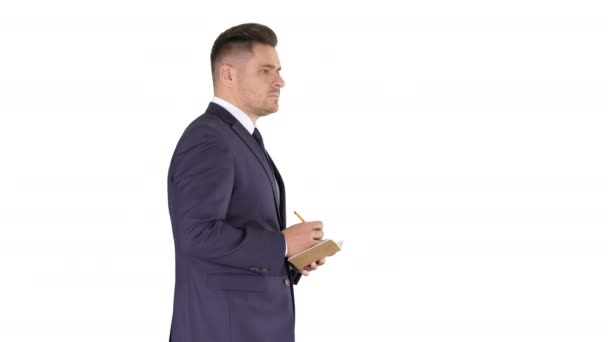 Jovem homem de negócios caucasiano positivo andando e fazendo checklist no fundo branco . — Vídeo de Stock
