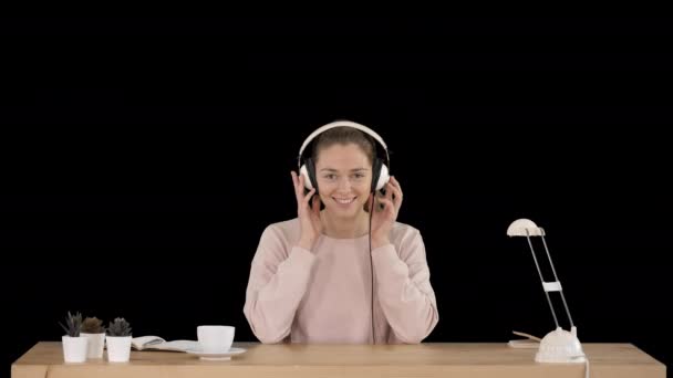 Mladá usměvavá žena si nasazuje sluchátka a poslouchá hudbu, Alpha Channel — Stock video