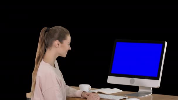Kız bilgisayar monitörü önünde oturan ve bir şey gülümseyen izlerken mavi ekran mock-up ekran, alfa kanal — Stok video