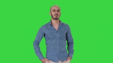 Rahat bir kıyafet yürüyüş giyen yakışıklı genç Arap adam, bir yeşil ekran üzerinde ceplerinde her iki elini koyarak, chroma key.