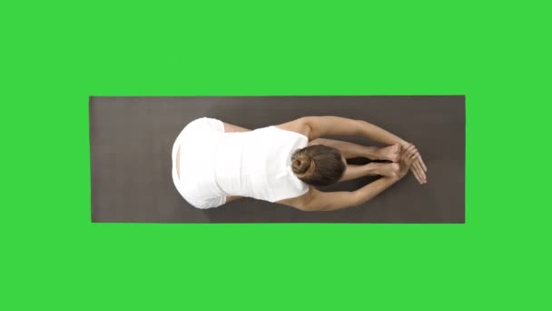 Giovane donna bionda attraente praticare yoga, facendo seduto esercizio piega in avanti, paschimottanasana posa su uno schermo verde, Chroma Key . — Video Stock