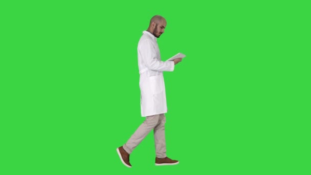 Doctor revisando su tableta caminando en una pantalla verde, Chroma Key . — Vídeos de Stock