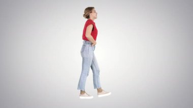 Fit kız degrade arka plan üzerinde yürüyen mavi kot ceplerinde ellerini tutarak.