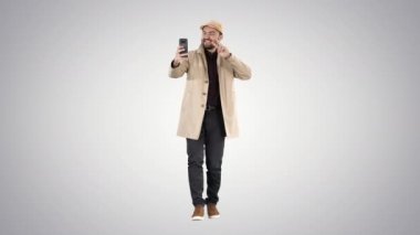 Ceketli neşeli adam degrade arka planda selfie çekerken fotoğraf çekiyor.