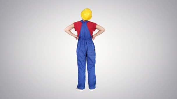 건축용 투구를 쓰고 있는 여자 기술자 가편 안 한 배경에 손을 엉덩이 위에 얹고 서 있다. — 비디오