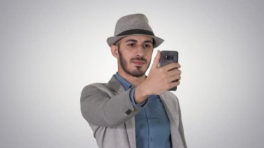 Rahat giysiler içinde Arap adam yürüyüş ve degrade arka planda selfie yapma.