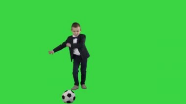 Resmi takım elbiseli sevimli bir çocuk Yeşil Ekranda bir topa vurmak, Chroma Key.