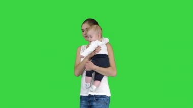 Genç anne Yeşil Ekranda bebeğini tutarken bir dikkat jesti yapıyor, Chroma Key.