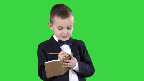 Αγόρι σε ένα επίσημο ρούχα γράφοντας σε λίστα ελέγχου ή σημειωματάριο σε μια πράσινη οθόνη, πλήκτρο αποχρώσεων. — Αρχείο Βίντεο