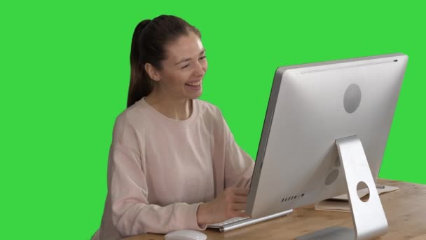 Femme heureuse ayant un appel vidéo assis devant son ordinateur sur un écran vert, Chroma Key . — Video