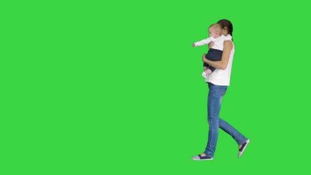 グリーンスクリーン、クロマキーで赤ちゃんを抱きながら注意ジェスチャーをする若い母親. — ストック動画