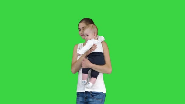 Jonge moeder die een attentie gebaar maakt terwijl ze haar baby vasthoudt op een groen scherm, Chroma Key. — Stockvideo