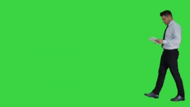 Yeşil Ekranda yürürken tablet kullanan zarif genç işadamı, Chroma Key.