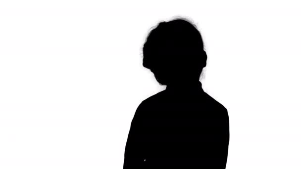 Silhouette niedliches Vorschulmädchen, das schüchtern dasteht, sich umschaut und nachdenkt. — Stockvideo