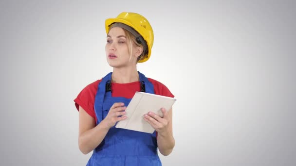 Ingeniera mujer revisando el plano del edificio en el panel táctil y mirando objetos, edificios a su alrededor en un fondo degradado. — Vídeo de stock