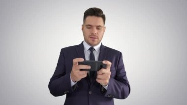 Yakışıklı işadamı akıllı telefonu ile oynuyor ve degrade arka planda kaybediyor.
