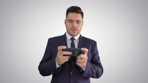 Knappe zakenman spelen met zijn smartphone en verliezen op gradiënt achtergrond. — Stockvideo