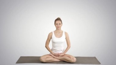 Genç güzel sarışın kadın yoga yapıyor ve degrade arka planda gülümseyen.