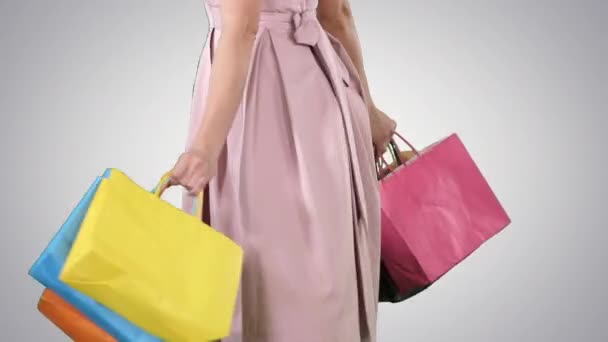 Vrouw het houden van boodschappentassen in haar handen en het maken van een turn op gradiënt achtergrond. — Stockvideo