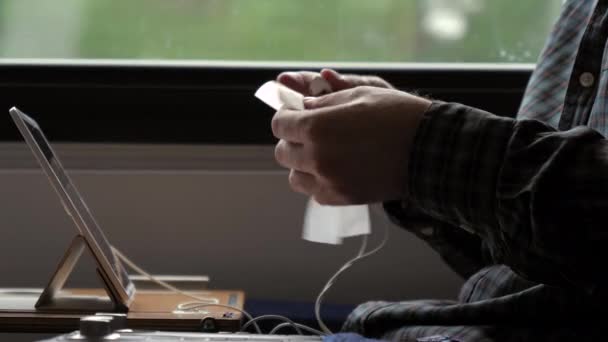 Hombre limpiando y limpiando auriculares con una servilleta en un tren. — Vídeo de stock