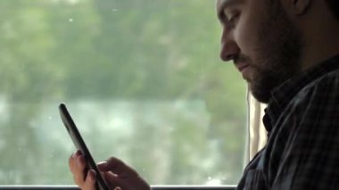 Trende akıllı telefonuyla internette sörf yapan yakışıklı bir adam..