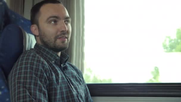 Привлекательный мужчина разговаривает с камерой во время езды на поезде. — стоковое видео