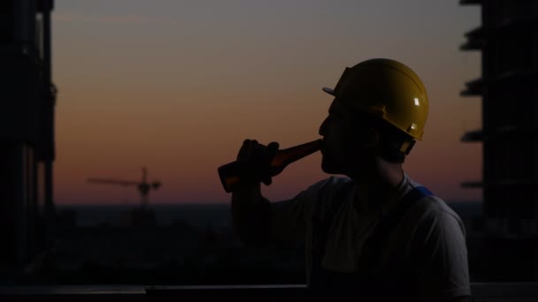 Trabajador de la construcción bebiendo cerveza en casco. — Vídeos de Stock