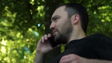 Parkta telefonla konuşan ciddi bir adam..