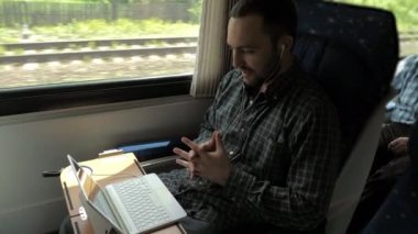 Trende laptopuyla sohbet eden bir adam..