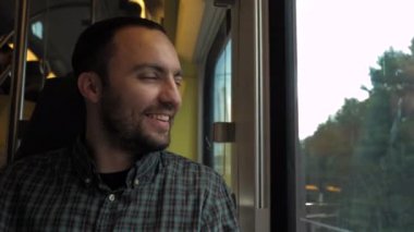 Iş yolculuğu sırasında cep telefonu üzerinde film Izlerken gülümseyen adam.