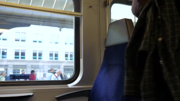 Jonge man die een stoel neemt bij het raam in een trein. — Stockvideo