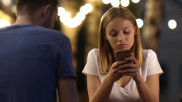 Uttråkad vacker ung kvinna på dålig dejt med sin telefon. — Stockvideo