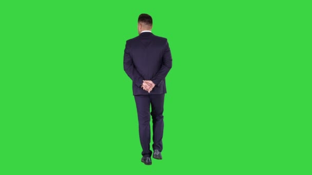 Empresario caminando y mirando a su alrededor tomados de la mano detrás de su espalda en una pantalla verde, Chroma Key . — Vídeo de stock