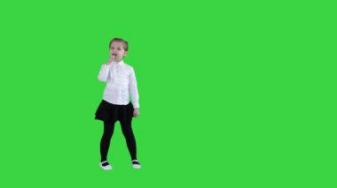 Sevimli mutlu kız bir yeşil ekranda hayali mikrofon içine şarkı, Chroma anahtar.