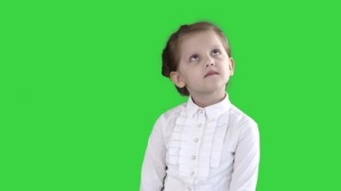 Sevimli okul öncesi kız ayakta bakmak ve yeşil ekran, Chroma anahtar üzerinde düşünme utangaç olmak.