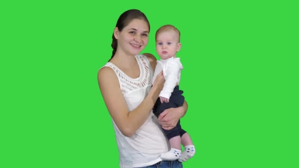 Schattige baby jongen in moeders handen op zoek naar camera op een groen scherm, Chroma Key. — Stockvideo