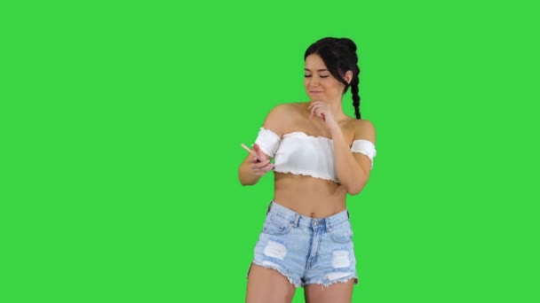 Позитивна досить сексуальна дівчина, яка слухає музику на своєму телефоні на зеленому екрані, Chroma Key. — стокове відео