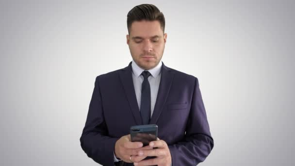 Serious businessman texting message on his phone on gradient background. — Stock Video