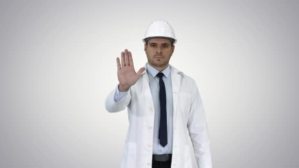 Engenheiro científico em capacete mostrando parar cantar e, em seguida, faz um gesto de atenção no fundo gradiente. — Vídeo de Stock