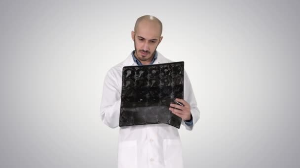Doktor przeglądając ramię rentgenowskie skanowania podczas chodzenia na tle gradientu. — Wideo stockowe