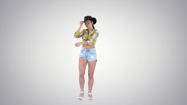 Young lady in a cowboy hat dancing on gradient background. — Stock Video