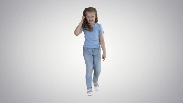 Klein schattig meisje het maken van een telefoontje tijdens het lopen op gradiënt achtergrond. — Stockvideo